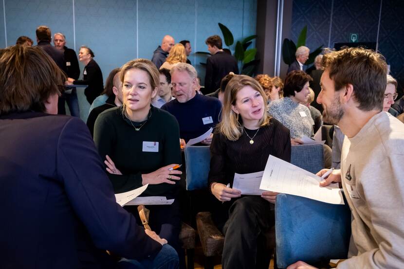 Mensen die aan een tafel zitten in gesprek tijdens bijeenkomst van de Nederlandse Sportraad op 11 februari